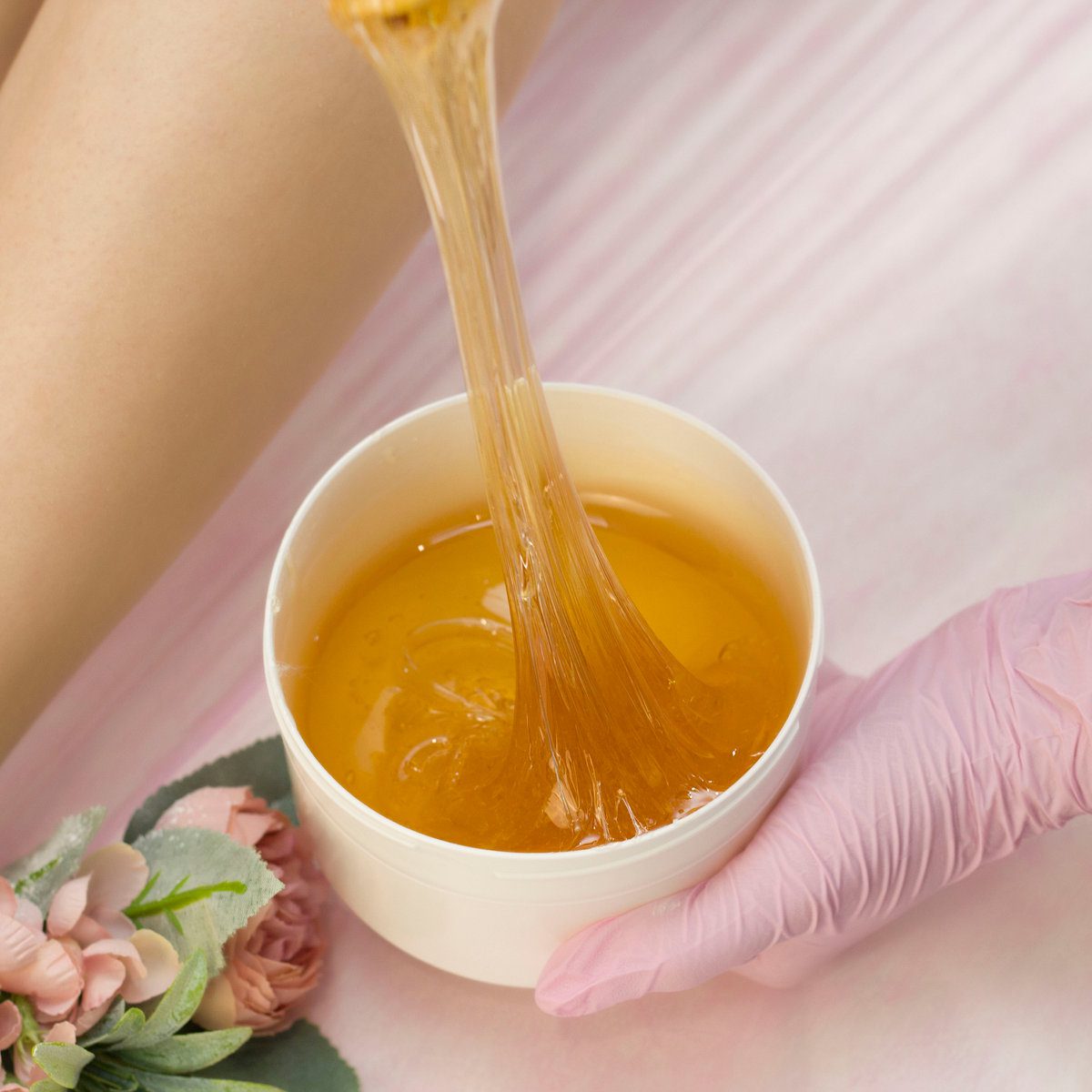 Hair removal in a luxury spa studio. Women's feet wax with saccharin. Hot sugar. The product of the wax bowl. Salon bank. Purple, lilac background
